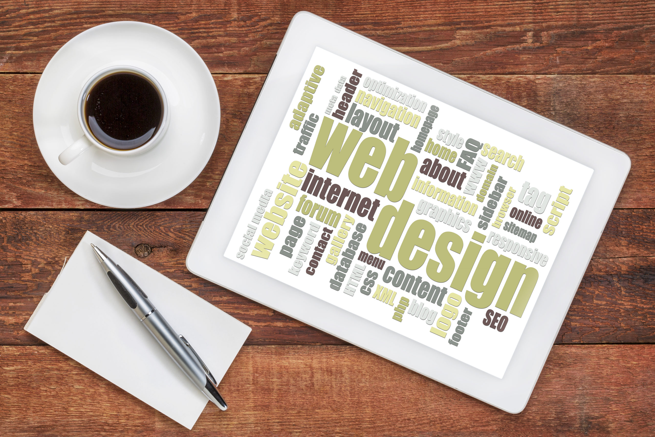 web design word cloud on a digital tablet with a cup of coffee on a rustic wooden table